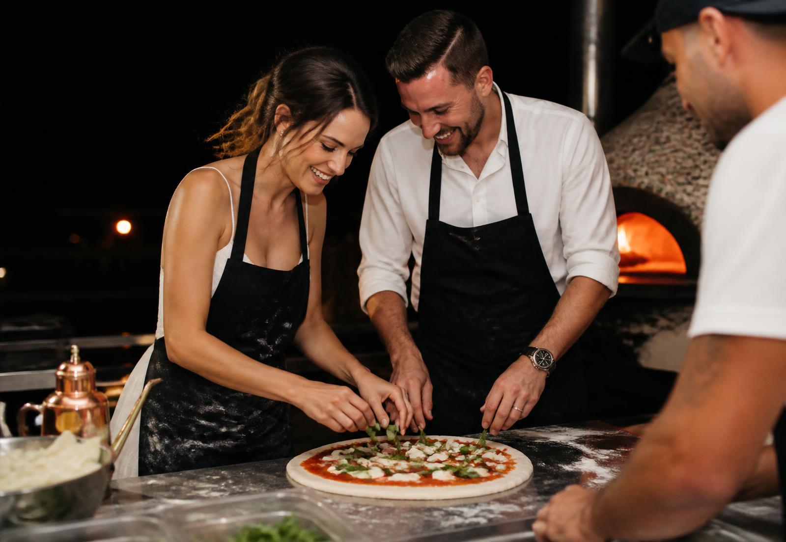 Novios con delantal preparando juntos su propia pizza junto al pizzaiolo