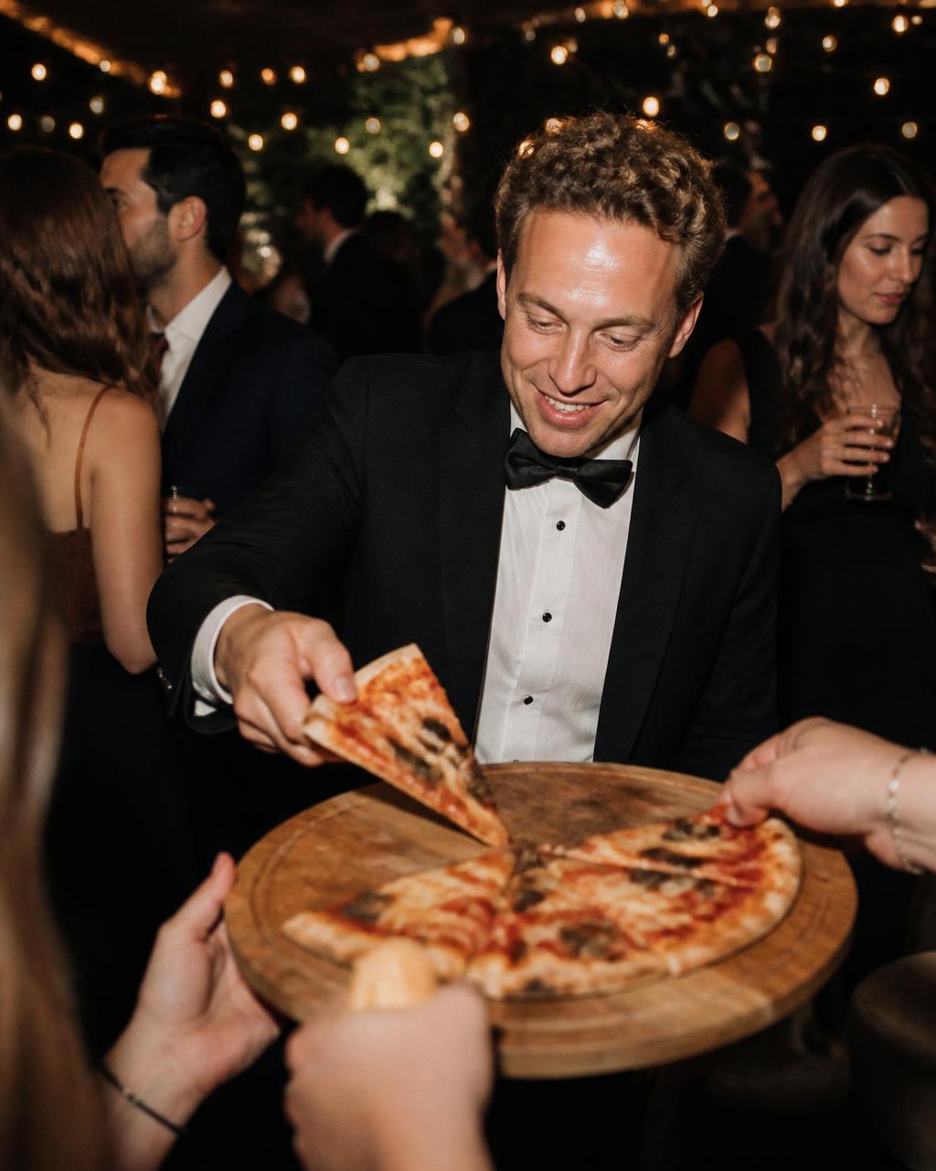 Invitado cogiendo una porción de pizza durante la fiesta
